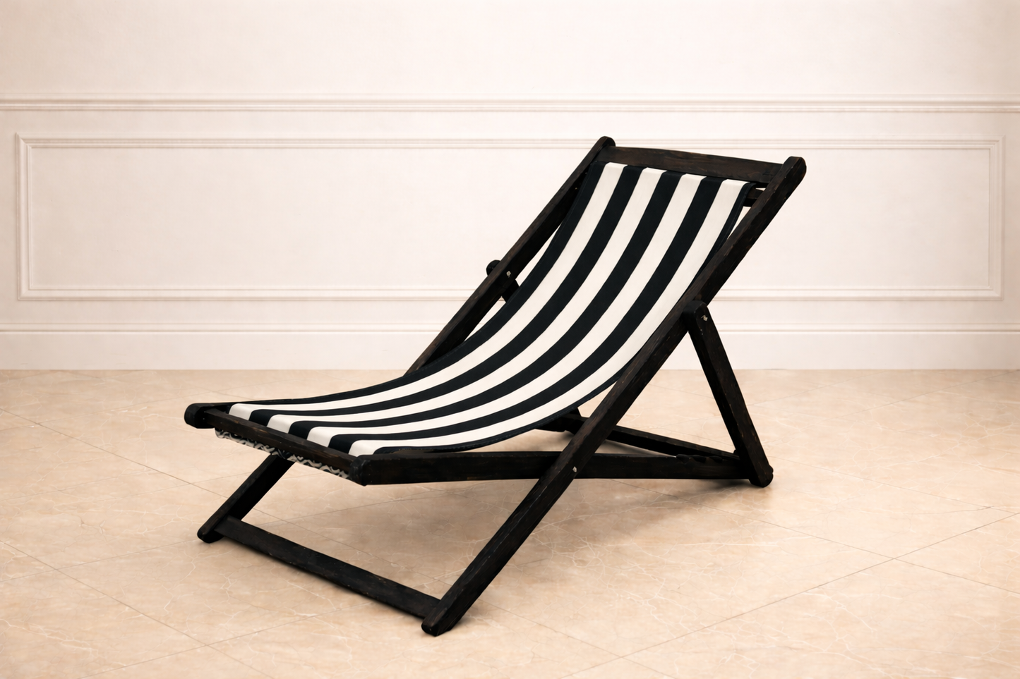 Black and white striped deck chair on a wooden floor with a white wall background