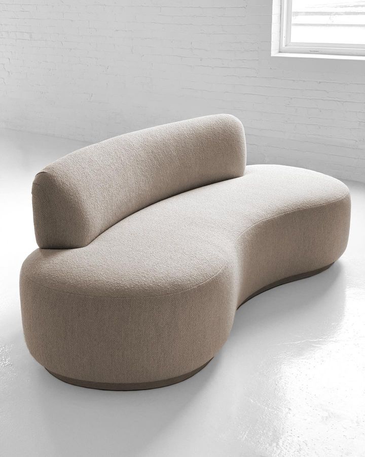 Modern beige sofa with curved design on a white floor and wall